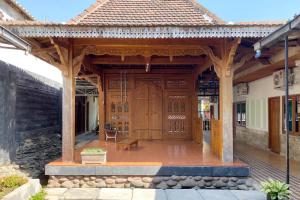 a wooden pavilion with a bench in front of a building at Adipura Guesthouse Syariah Mitra RedDoorz near Terminal Nganjuk in Nganjuk