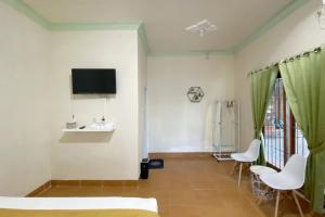 a room with a bed and two chairs and a tv at Adipura Guesthouse Syariah Mitra RedDoorz near Terminal Nganjuk in Nganjuk