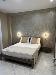 a bed in a bedroom with two lights on the wall at B&B Lamezia Central Airport in SantʼEufemia Lamezia