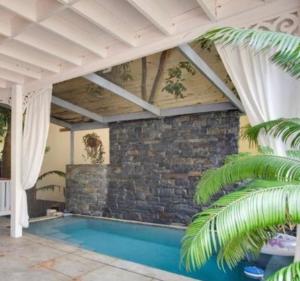 a swimming pool in a house with a brick wall at Alux House in Placencia