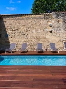 eine Gruppe von Stühlen neben einem Pool in der Unterkunft Maison et table d'hôtes Le Camélia Blanc in Saint-Ciers-sur-Gironde
