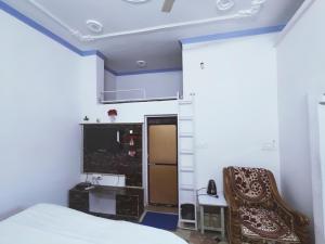 a bedroom with a bed and a chair and a television at Eastern Gate Homestay in Khajurāho