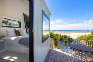 a bedroom with a bed and a balcony with a table and chairs at Reflections Byron Bay - Holiday Park in Byron Bay