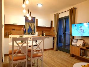 a kitchen and living room with a table and a tv at Apartmani Višegradski pogled in Višegrad