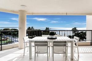 a white table and chairs on a balcony with a view of the ocean at Aquarius Luxury Apartment in Cairns
