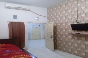 a room with a bed and a tv and a door at OYO 92816 Ana Homestay in Banyuwangi