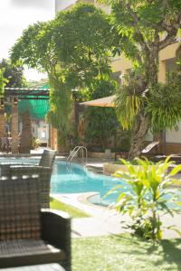 una piscina en un complejo con sillas y árboles en La Vintage Resort, en Patong Beach