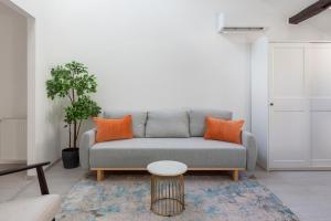 een woonkamer met een grijze bank en oranje kussens bij Rustic Central Studios by LH in Boedapest