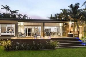 a modern house with glass walls and a patio at Ripples on the Beach - Beachfront Mission Beach in Mission Beach