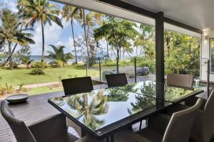 a dining room with a glass table and chairs at Ripples on the Beach - Beachfront Mission Beach in Mission Beach
