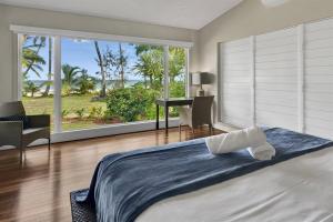 a bedroom with a bed and a desk and a window at Ripples on the Beach - Beachfront Mission Beach in Mission Beach