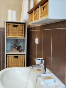 a bathroom with a sink and aaucet and baskets at Apartmani Roko in Okrug Donji