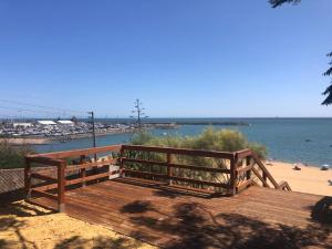 un banco de madera sentado en la parte superior de una playa en Apartamentos Luxury Mazagón, en Palos de la Frontera