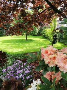 un jardin avec des fleurs roses et une cour verdoyante dans l'établissement Dreilärchenhaus, à Brixen im Thale