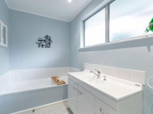 La salle de bains est pourvue d'un lavabo, d'une baignoire et d'une fenêtre. dans l'établissement The Airport Homestay House, à Christchurch