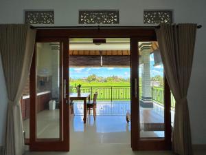 a dining room with a door open to a balcony at Bhakti Ubud Villa in Ubud