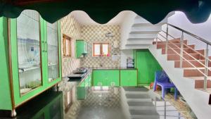 une cuisine avec des armoires vertes et un escalier dans l'établissement La Flora kodaikanal, à Kodaikānāl