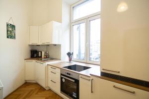 uma cozinha com armários brancos, um lavatório e uma janela em Raimond Apartment em Viena