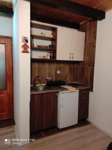 a kitchen with wooden cabinets and a white refrigerator at Planinska kuca Gora in Mitrovac
