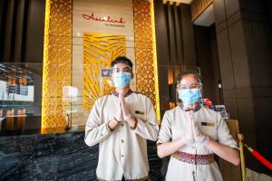 dos personas parados frente a un edificio con máscaras en Asialink Hotel Batam by Prasanthi, en Nagoya