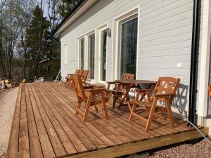 eine Holzterrasse mit Stühlen und einem Tisch auf einem Haus in der Unterkunft Comfortable villa with a hot tub 