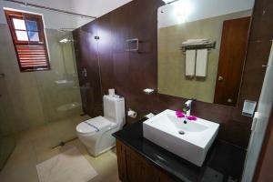 a bathroom with a sink and a toilet and a mirror at Hotel Tamarind Tree in Tissamaharama