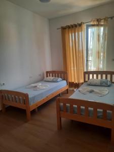 two twin beds in a room with a window at Vila Lefteria in Këlcyrë