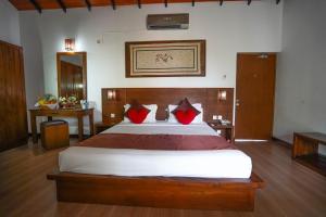 a bedroom with a large bed with red pillows at Hotel Tamarind Tree in Tissamaharama