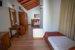 een slaapkamer met 2 bedden, een bureau en een spiegel bij Hotel Tamarind Tree in Tissamaharama