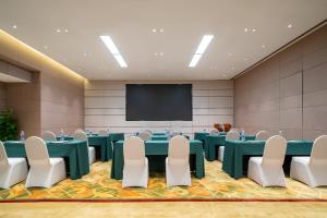 Holiday Inn Shanghai Hongqiao Central, an IHG Hotel في شانغهاي: قاعة اجتماعات مع طاولات وكراسي وشاشة