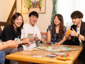 un grupo de personas sentadas alrededor de una mesa jugando un juego en Tokachi Nakasatsunai Glamping Resort Feriendorf, en Naka-satsunai