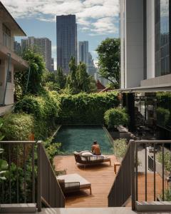 a man sitting in a bath tub in a pool on a balcony at Homm Sukhumvit34 Bangkok - a brand of Banyan Group in Bangkok