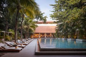 a resort pool with lounge chairs and palm trees at Plantation Urban Resort & Spa in Phnom Penh