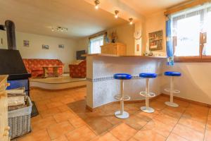 a kitchen with two bar stools and a living room at Chalupa Prášily in Prášily