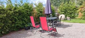 a table and chairs with an umbrella in a garden at Guest House Tidaholm in Tidaholm