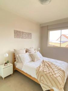 a bedroom with a bed with white sheets and a window at Apartment in Chiswick with Pool, sauna & Gym in Sydney