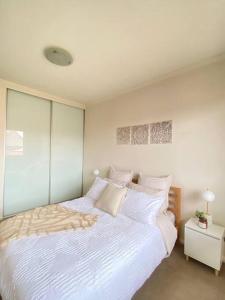 a bedroom with a large bed with white sheets and pillows at Apartment in Chiswick with Pool, sauna & Gym in Sydney