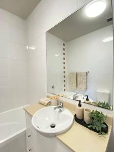 a white bathroom with a sink and a mirror at Apartment in Chiswick with Pool, sauna & Gym in Sydney