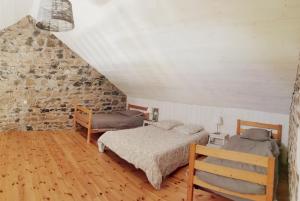 a bedroom with two beds and a brick wall at La Maison des Biscuits in Loubaresse