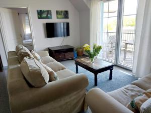 a living room with couches and a television and a table at Hochwertige Ferienwohnung direkt am Hafen mit Balkon in Ostseebad Karlshagen