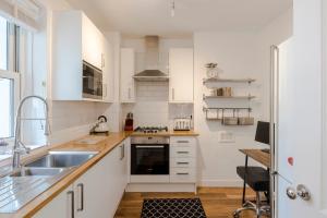 a kitchen with white cabinets and a sink at Central Euston One Bedroom Home in London