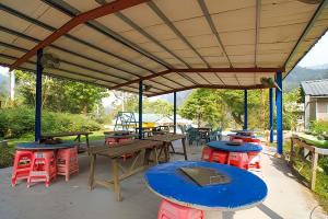 a patio with tables and stools under awning at 蓬萊生態農場仙山民宿 in Nanzhuang