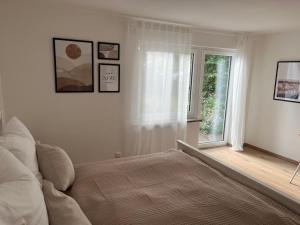 ein weißes Schlafzimmer mit einem Bett und einem Fenster in der Unterkunft Moderne Ferienwohnung in der Festspielstadt Bayreuth - zentral und dennoch ruhig gelegen in Bayreuth