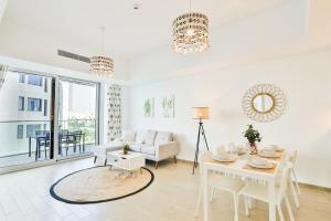 a white living room with a table and a couch at Voyage One Bedroom In Mayan in Abu Dhabi