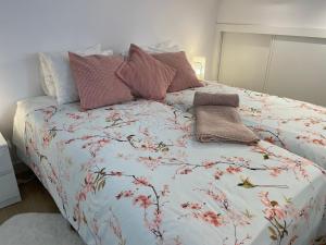 a bed with a floral comforter and pillows on it at Pink Home in Santiago de Compostela