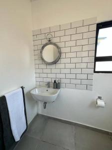a white bathroom with a sink and a mirror at The Urban Hub in Block 5 in Gaborone