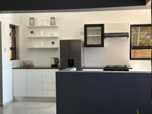 a kitchen with white cabinets and a black counter top at The Urban Hub in Block 5 in Gaborone