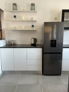 a kitchen with a stainless steel refrigerator and white cabinets at The Urban Hub in Block 5 in Gaborone