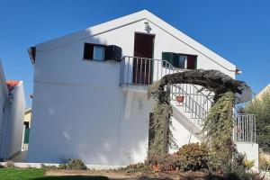 ein weißes Haus mit einem Bogen davor in der Unterkunft Calma na Lagoa de Albufeira, Castelo Sesimbra. in Sesimbra