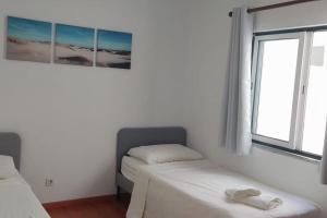 a bedroom with two beds and two windows at Calma na Lagoa de Albufeira, Castelo Sesimbra. in Sesimbra